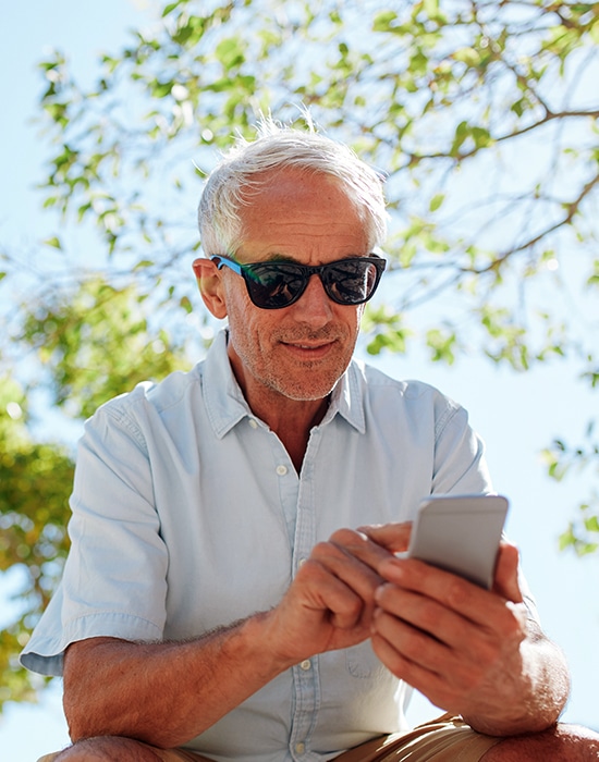 Hombre mayor navega por Internet a través de su teléfono móvil en un parque público