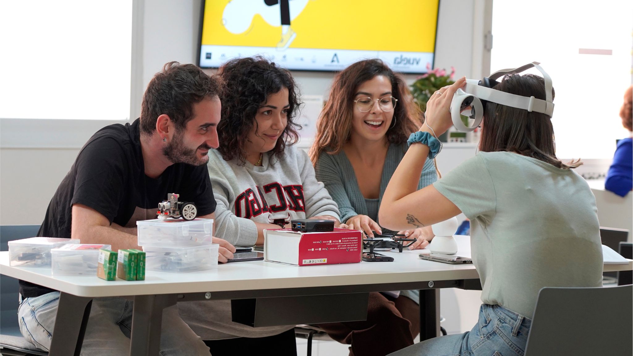 Grupo de jóvenes colaborando en un taller tecnológico con dispositivos de realidad virtual y robótica