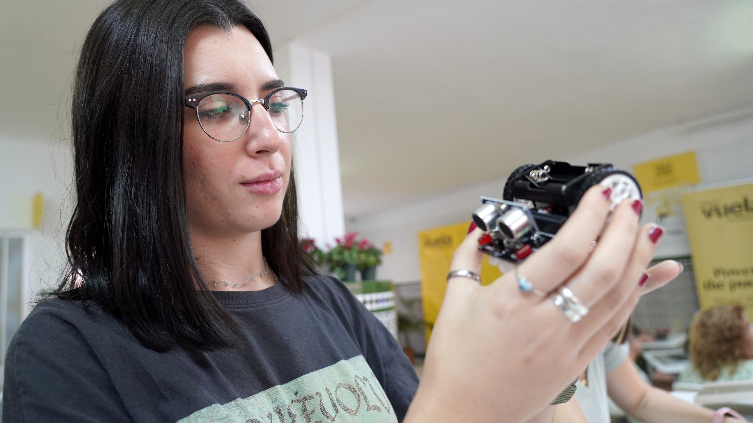 Primer plano de una usuaria examinando con detalle un prototipo de robótica educativa durante una sesión práctica.