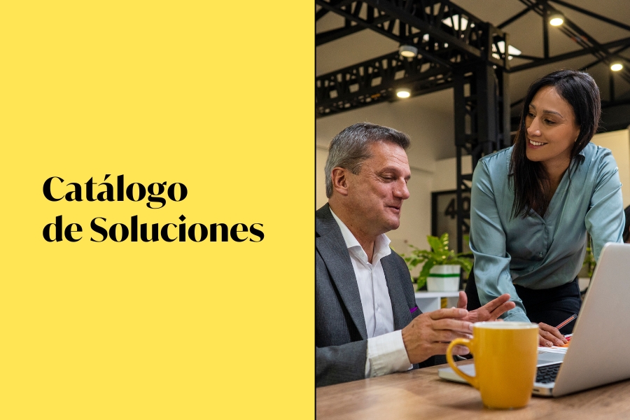 Un hombre y una mujer en una oficina. Ambos charlan mirando un portátil