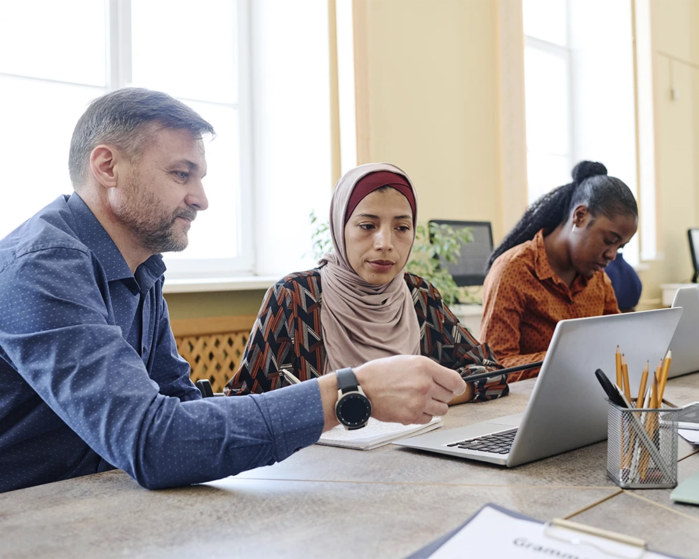 Docente ayuda a participante en un curso sobre formación digital dirigido a colectivos en riesgo de exclusión