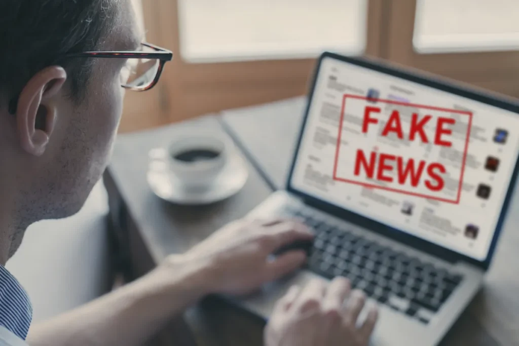 Persona leyendo noticias en un ordenador portátil mientras en la pantalla aparece el mensaje “Fake News”, relacionado con la desinformación en internet.