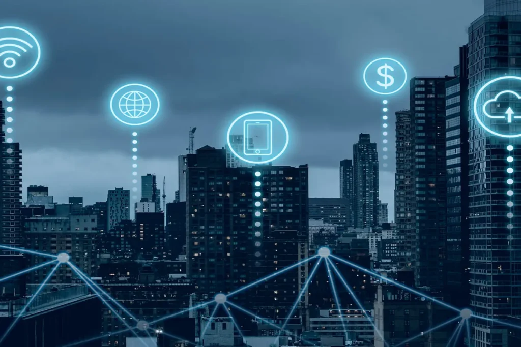 Vista de una ciudad con edificios y rascacielos sobre la que aparecen iconos digitales de wifi, internet, dispositivos y servicios en la nube conectados en red.
